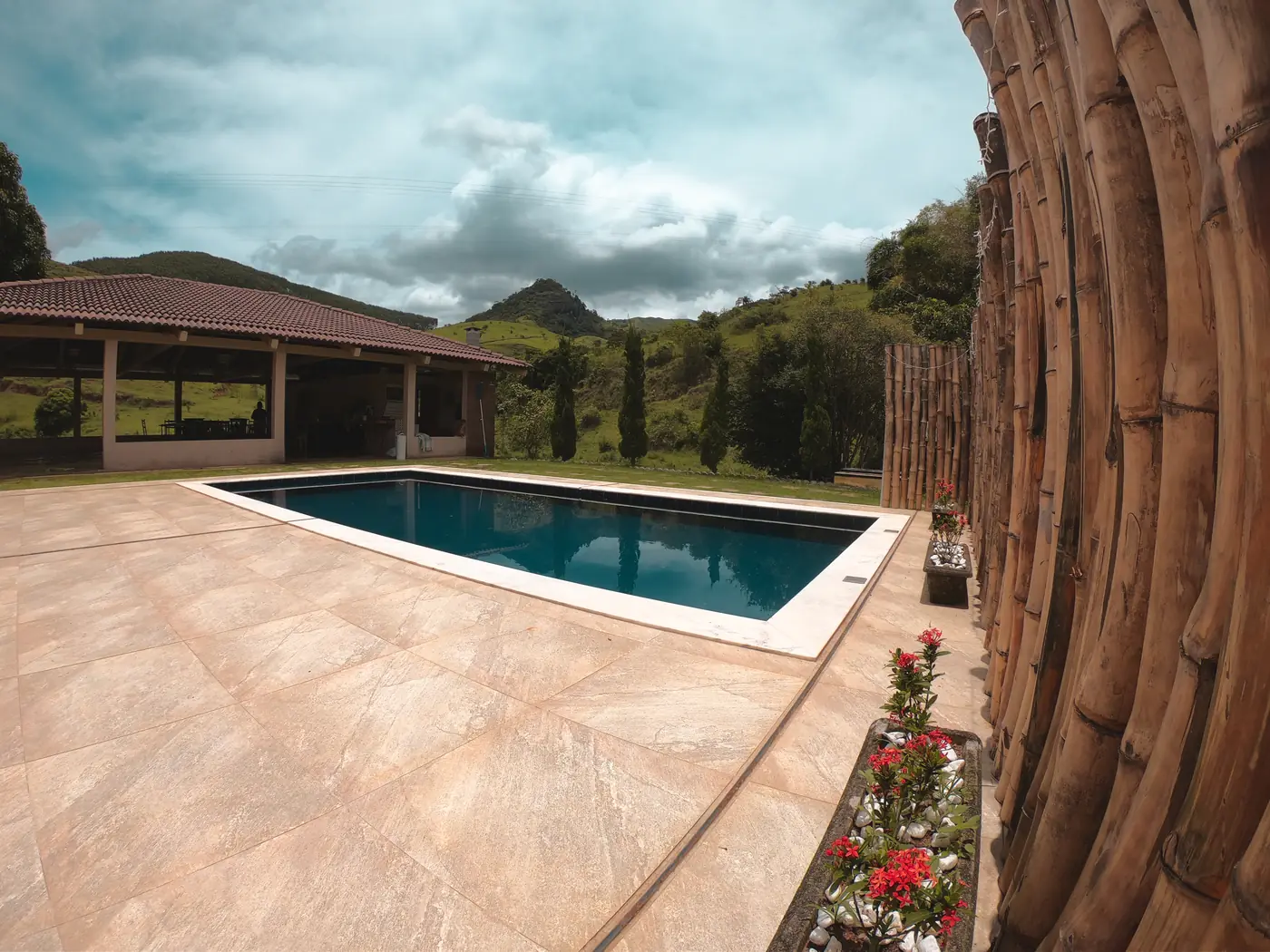Deck da piscina com cerca de bambu e vista para a serra