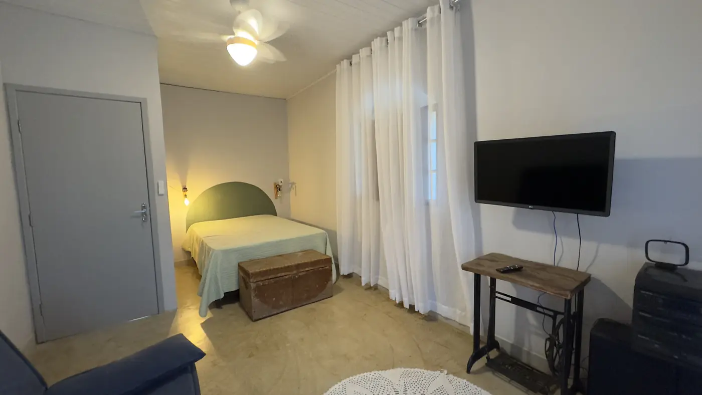Quarto com cama de casal, TV e ventilador de teto