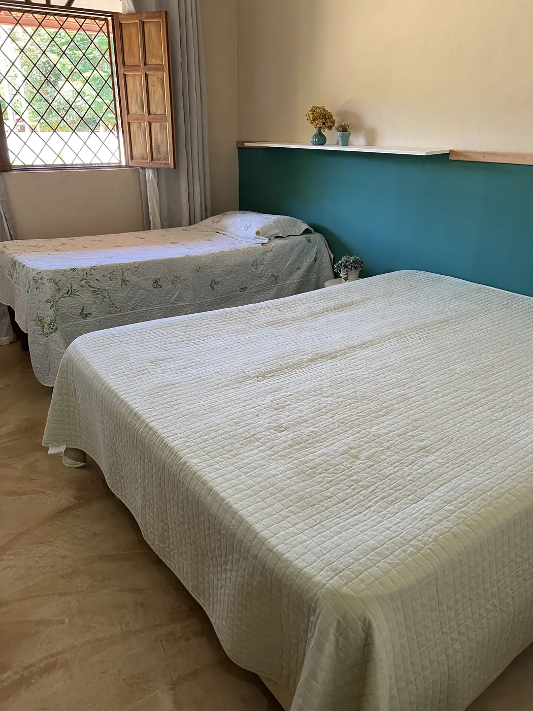 Quarto com cama de casal e de solteiro, parede verde